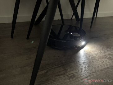 Le Roborock Qrevo Slim avec sa lumière allumée dans le labyrinthe des pieds de chaise