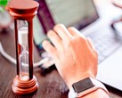 Un sablier à côté d’une main posée sur le clavier d’un ordinateur portable