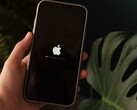 Une main tient un iPhone ; le logo Apple et une barre de progression s'affichent à l'écran.
